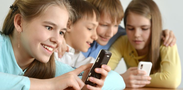 Photo of children smiling and playing on smarphones