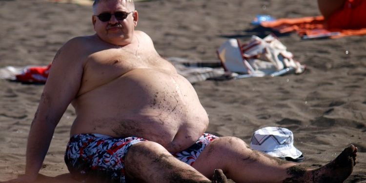 Image of the man suffering from obese on the beach