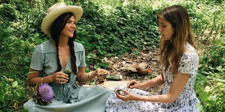 Wellness warrior Amanda Chantal Bacon and her friend eating snacks that tap into the natural healing power of raw vegetables, fruits, petals, herbs, roots, nuts, and seaweeds 