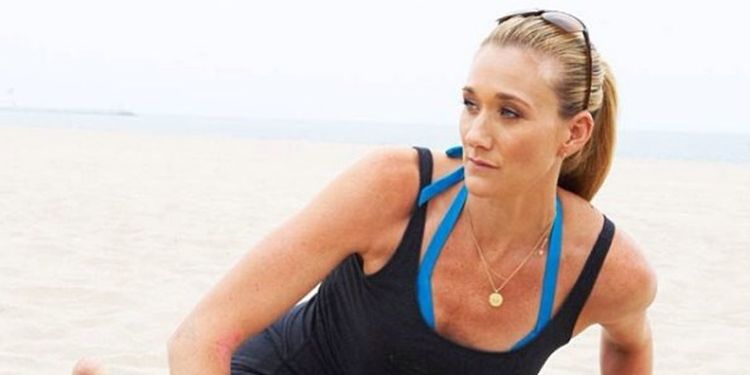 Wellness warrior Kerri Walsh Jennings is stretching on the beach. 