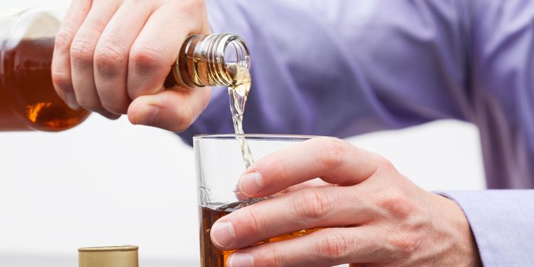 Photo of a man filling glass with alcohol drink