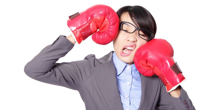 Photo of Asian girl with glasses kicking herself with boxing gloves