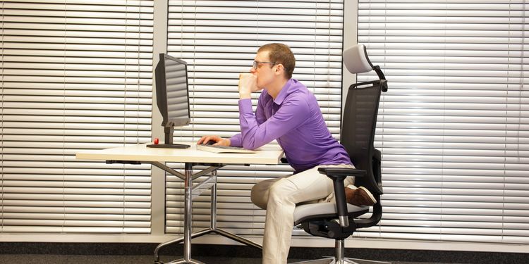 Photo of a man sitting behind the desk in bad posture