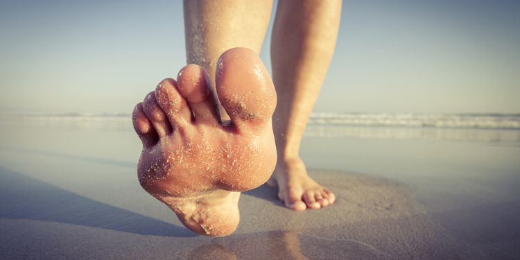 Close up of a woman walking on wet sand on the beach