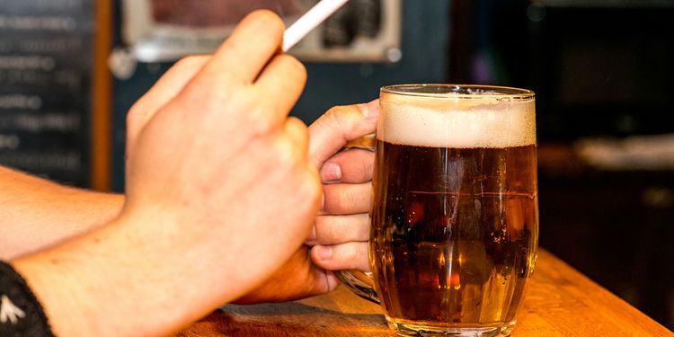 Photo of man drinking beer and smoking at bar