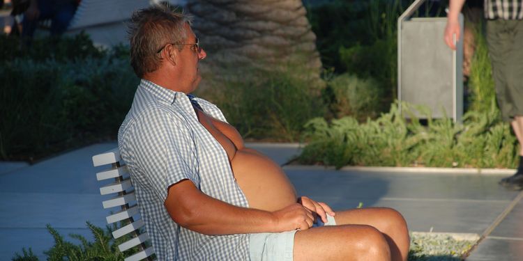 Photo of a bloated man sitting on a bench