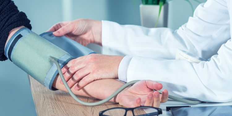 Photo of a doctor cardiologist measuring blood pressure of female patient in hospital office