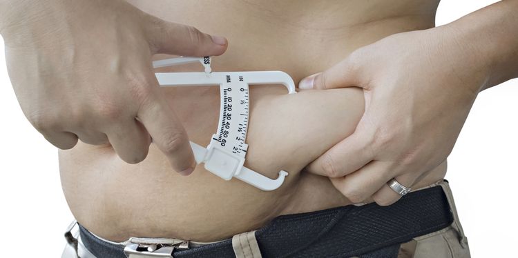 Photo of obese man measuring waist with calipers