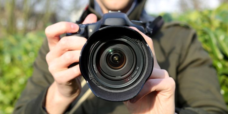 Photo of a man holding camera with large lens