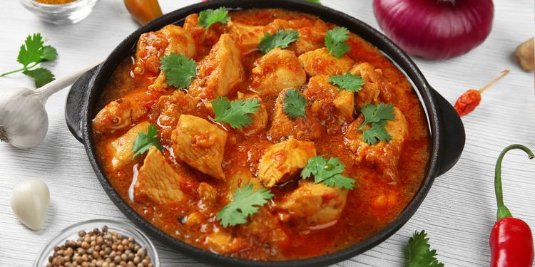 Photo of chicken curry with vegetables on wooden background