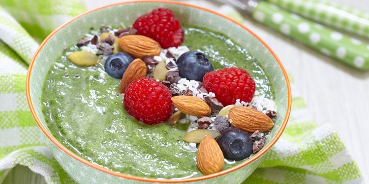 Photo of coconut green smoothie in a bowl with nuts and berries