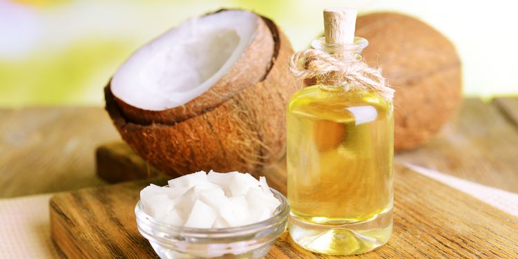 Coconut oil bottle with slices of coconut on table