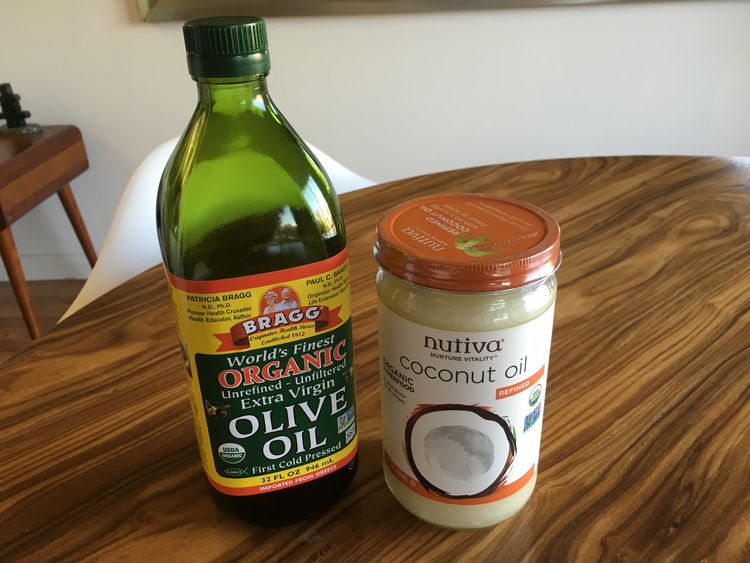 Bottle of olive oil next to a bottle of coconut oil