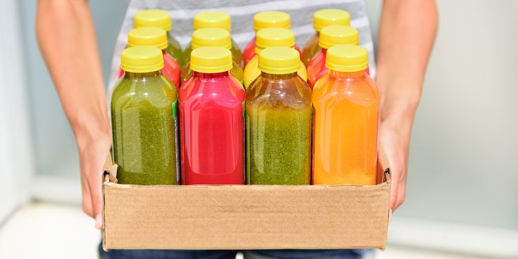 Photo of a person holding different colored bottles of cold pressed juice