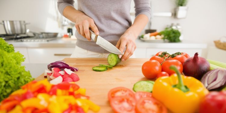 Photo of a woman cutting vegetables in kitchen