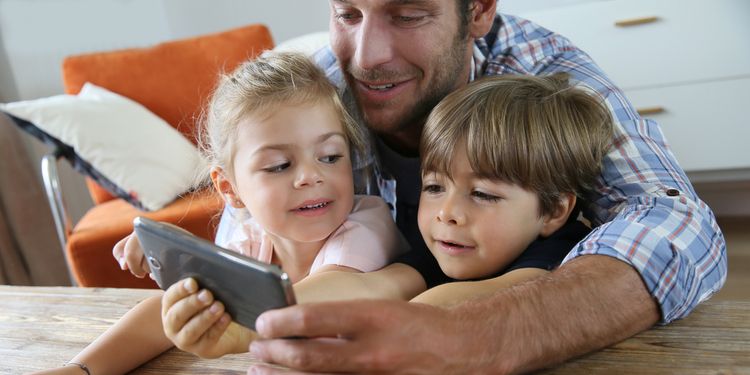 Photo of father and his kids playing with smartphone