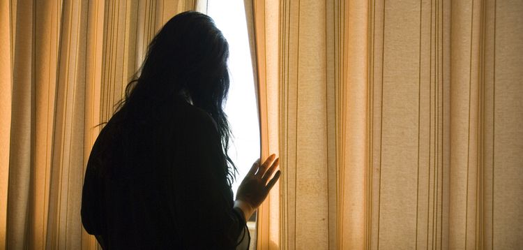 Photo of a woman at window in dark room