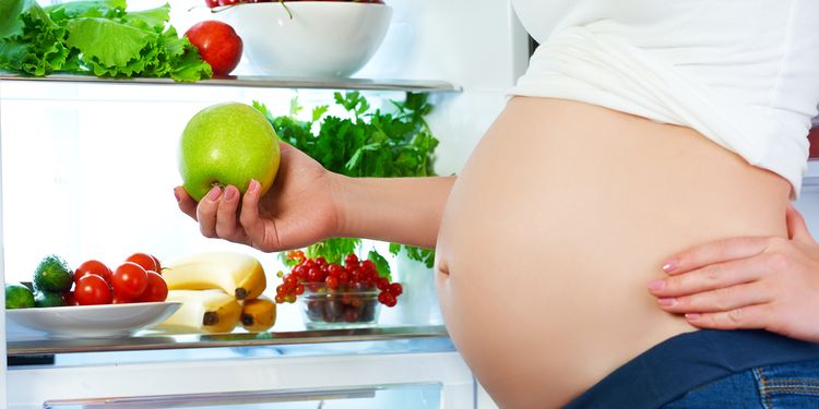 Photo of a pregnant woman holding a green apple