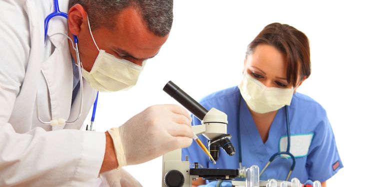 Photo of a doctor and nurse looking through the microscope