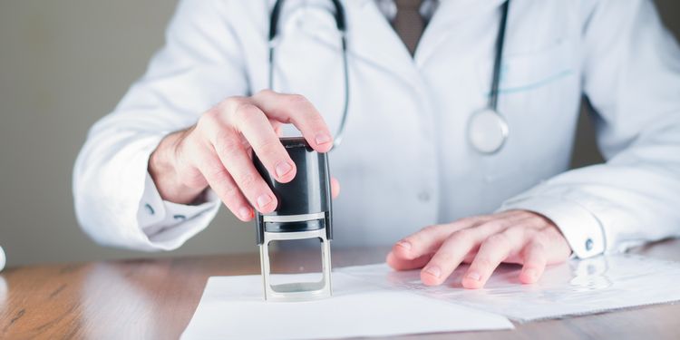 Photo of physician in office hitting the seal on the paper