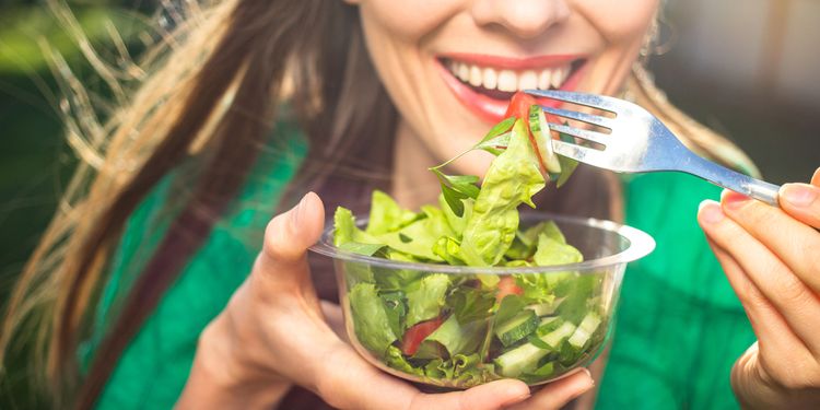 Photo of a smiling woman eating salad