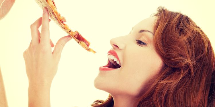 Photo of a woman eating slice of pizza