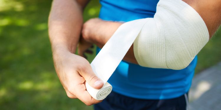 Photo of a man bandaging his elbow