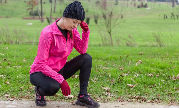 Photo of a woman having headache while jogging