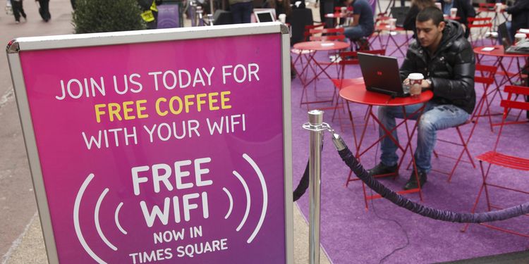 Photo of people sitting in open wifi cafe surfing internet