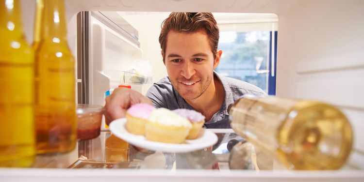 Photo of a man pulling cake out of the fridge