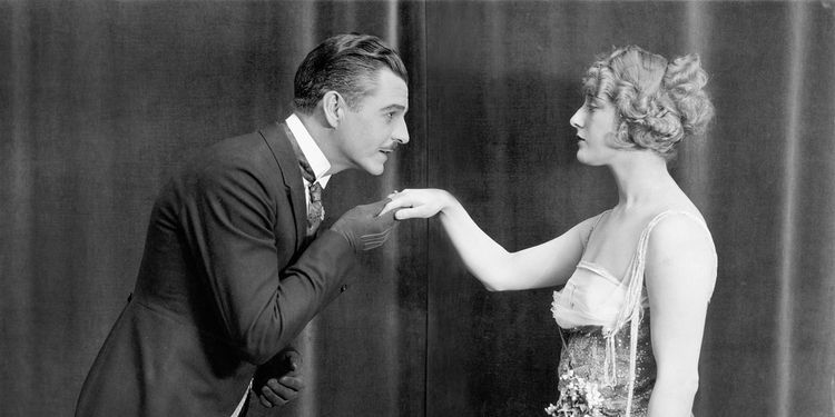 Old black and white photo of gentleman kissing lady's hand