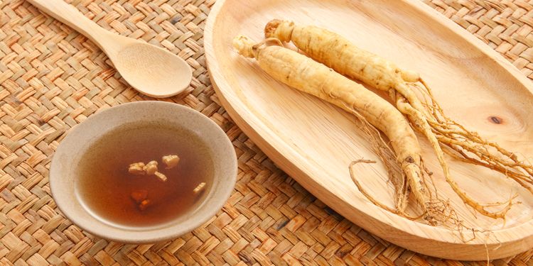 Photo of ginseng tea in cup next to its root