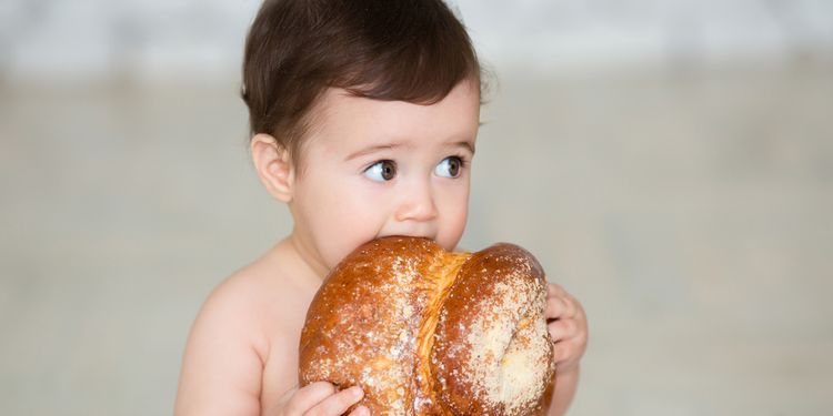 Photo of baby biting a piece of bread