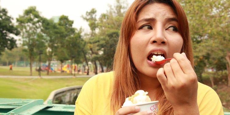 Photo of woman eating ice cream feeling guilty