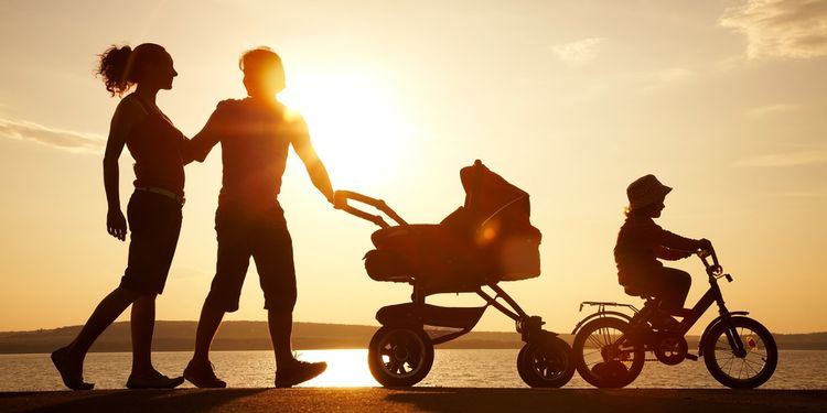 Photo of a happy family walking at the beach with sunset in background