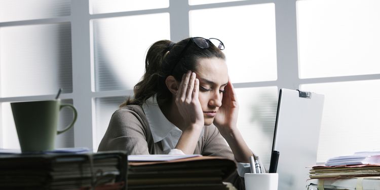 Photo of woman holding her head, having migraine in office