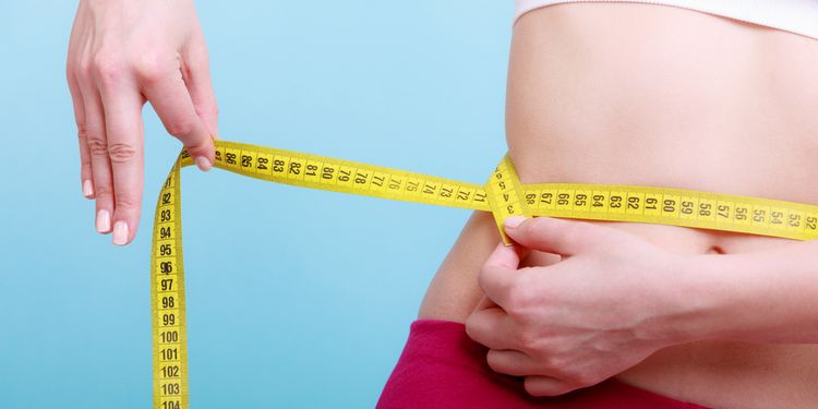 Photo of a woman measuring her waist size