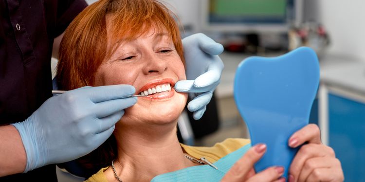 Photo of a smiling senior woman with new dental implants sitting in the dental office