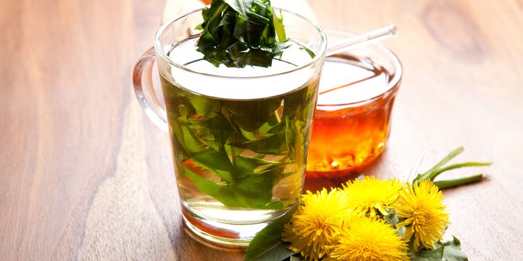 Photo of herbal tea and a dandelion flowers on table