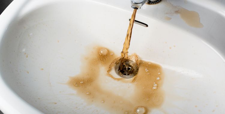 Photo of dirty brown water running into a white sink