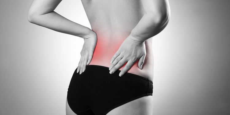 Photo of woman holding her lower back region in pain