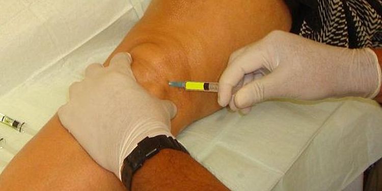 Photo of physician giving knee injection to a patient