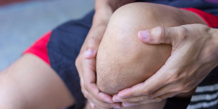 Photo close up of a man holding the painful knee