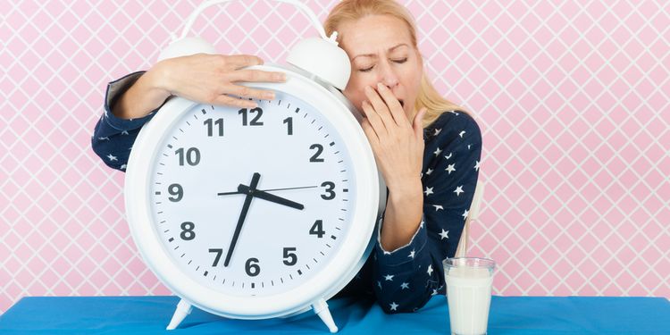 Photo of woman hugging a clock and yawning