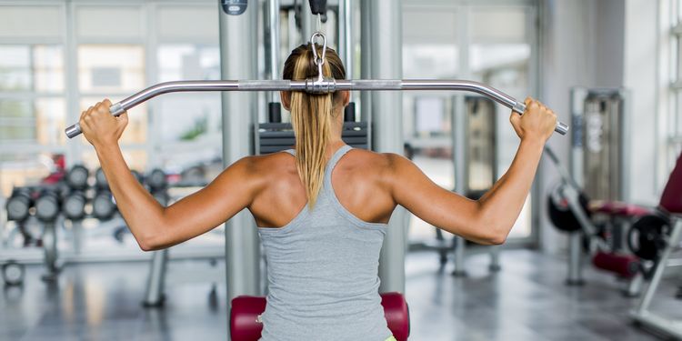 Pretty blonde girl doing lat pulldown at the gym