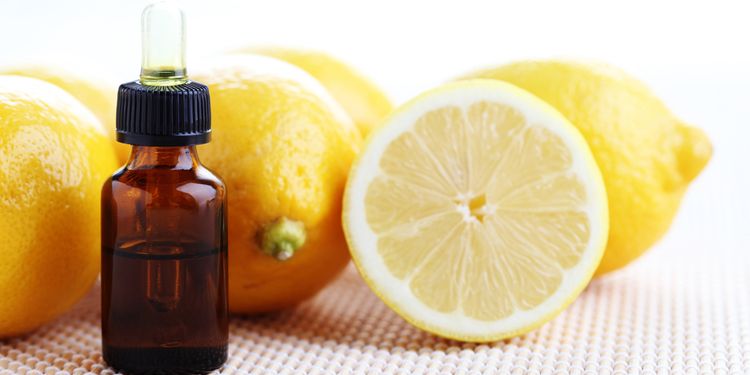 Photo of a lemon essential oil bottle next to halves of lemon