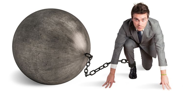 Photo of a businessman in low runner start with large prison ball and chain attached to his ankle