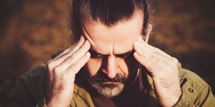 Photo of a man with headache holding his head with his hands