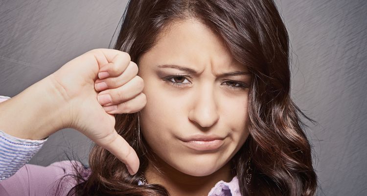 Photo of a girl with disappointed expression on face showing her thumb down