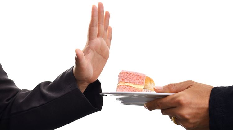 Photo of a hand refusing the offer of sugary cake